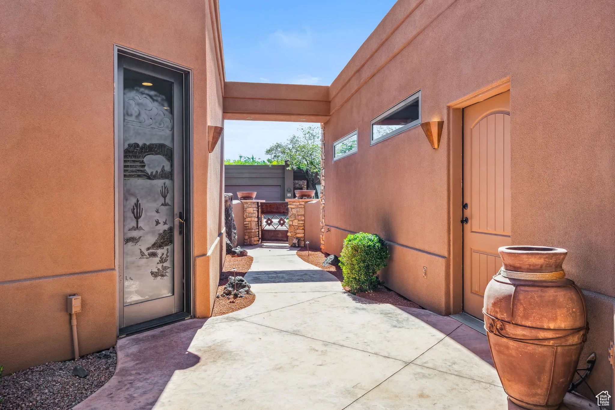 Property entrance featuring stucco siding, a gate, and a patio