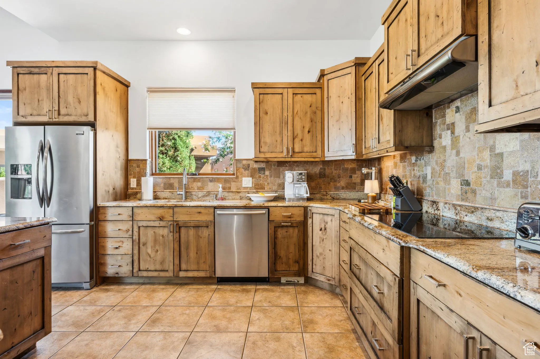 Kitchen with stainless steel appliances, under cabinet range hood, a sink, backsplash, and recessed lighting