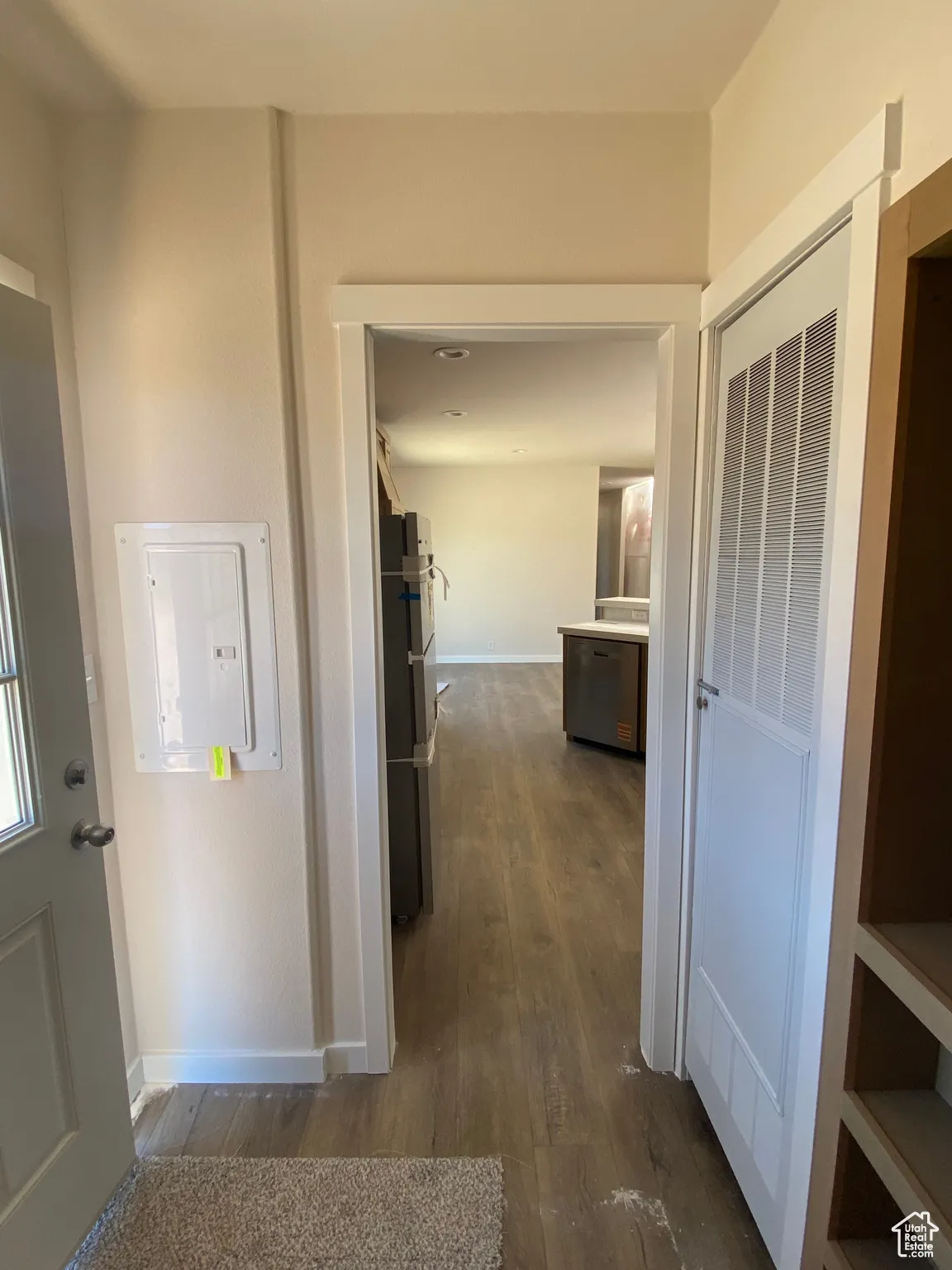 Corridor with dark wood-type flooring, baseboards, and electric panel