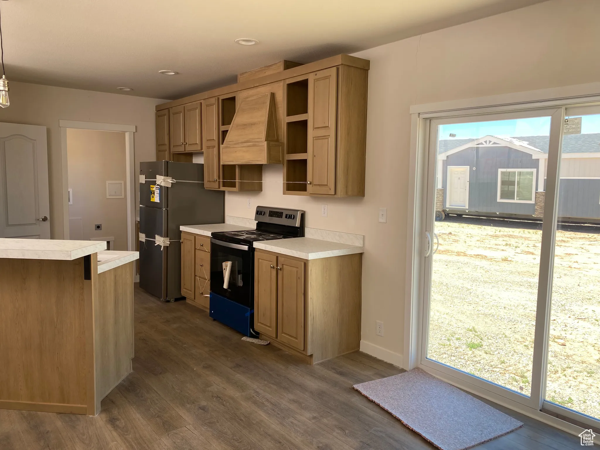 Kitchen with stainless steel electric range oven, freestanding refrigerator, light countertops, dark wood-style floors, and recessed lighting