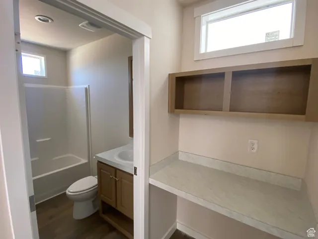Bathroom with vanity, toilet, wood finished floors, and a bathtub