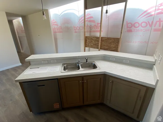 Kitchen featuring dishwasher, a sink, dark wood-style floors, and light countertops