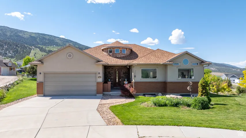 View of front of home with a garage, a mountain view, concrete driveway, and a front lawn