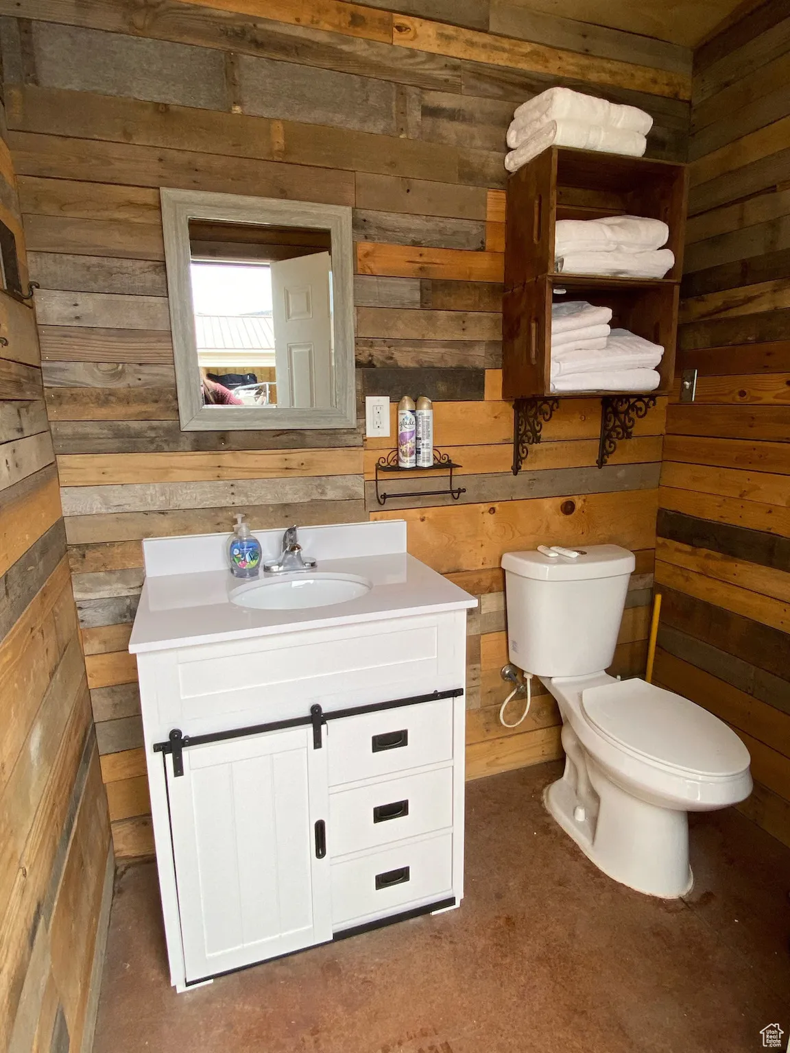 Bathroom with wood walls, vanity, and toilet