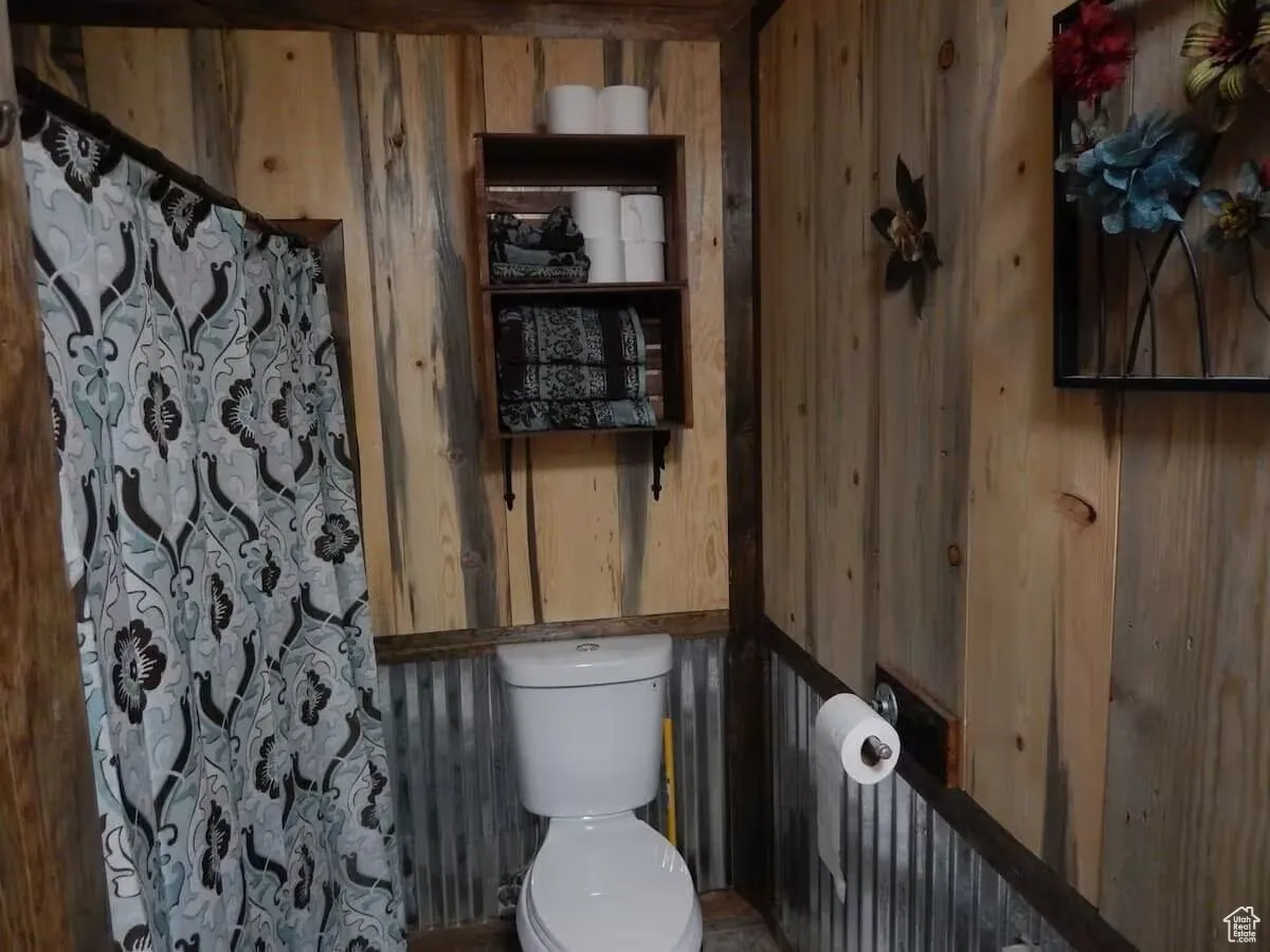 Full bath featuring wood walls and toilet