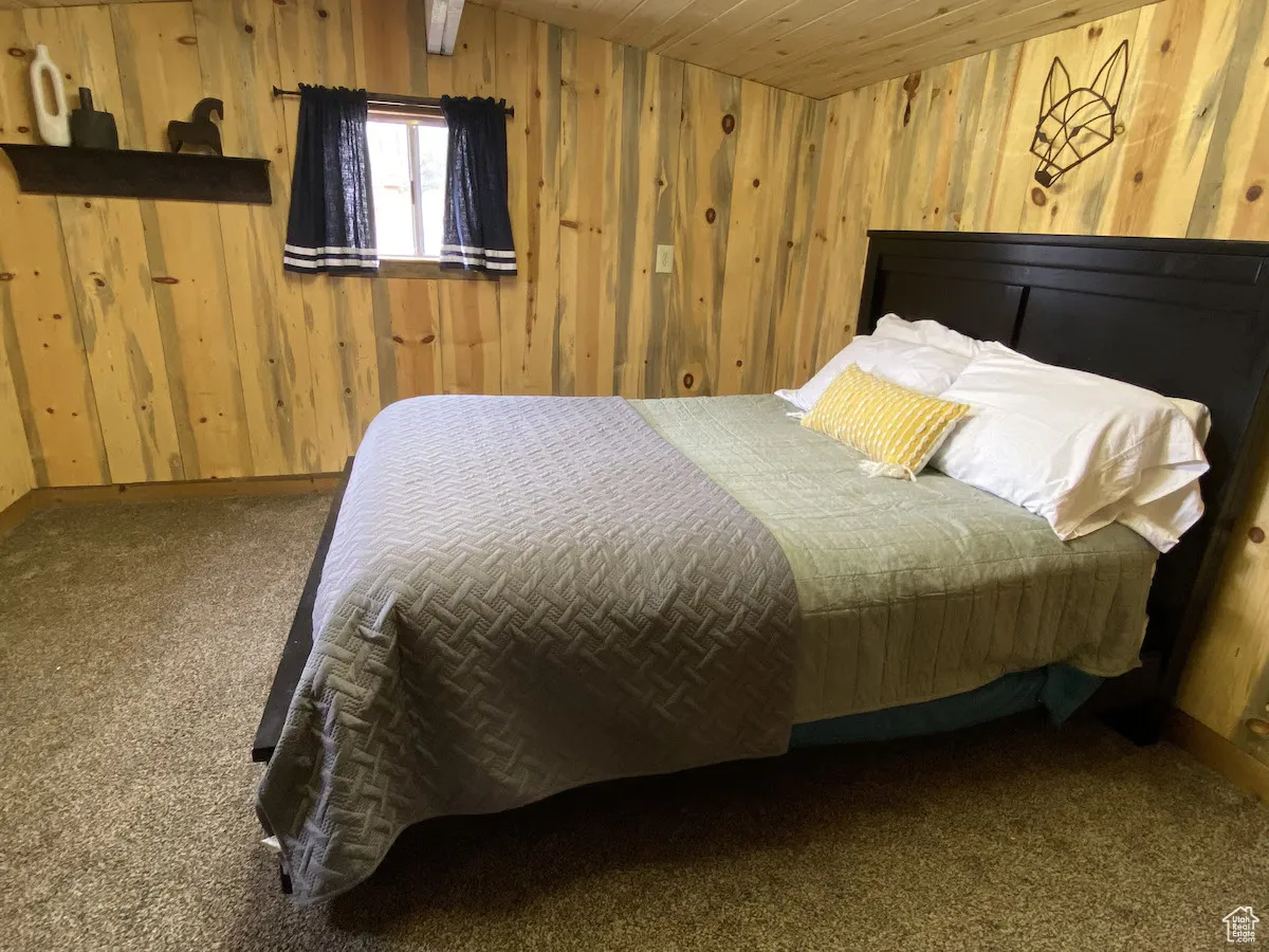 Bedroom featuring wooden walls, carpet, and baseboards