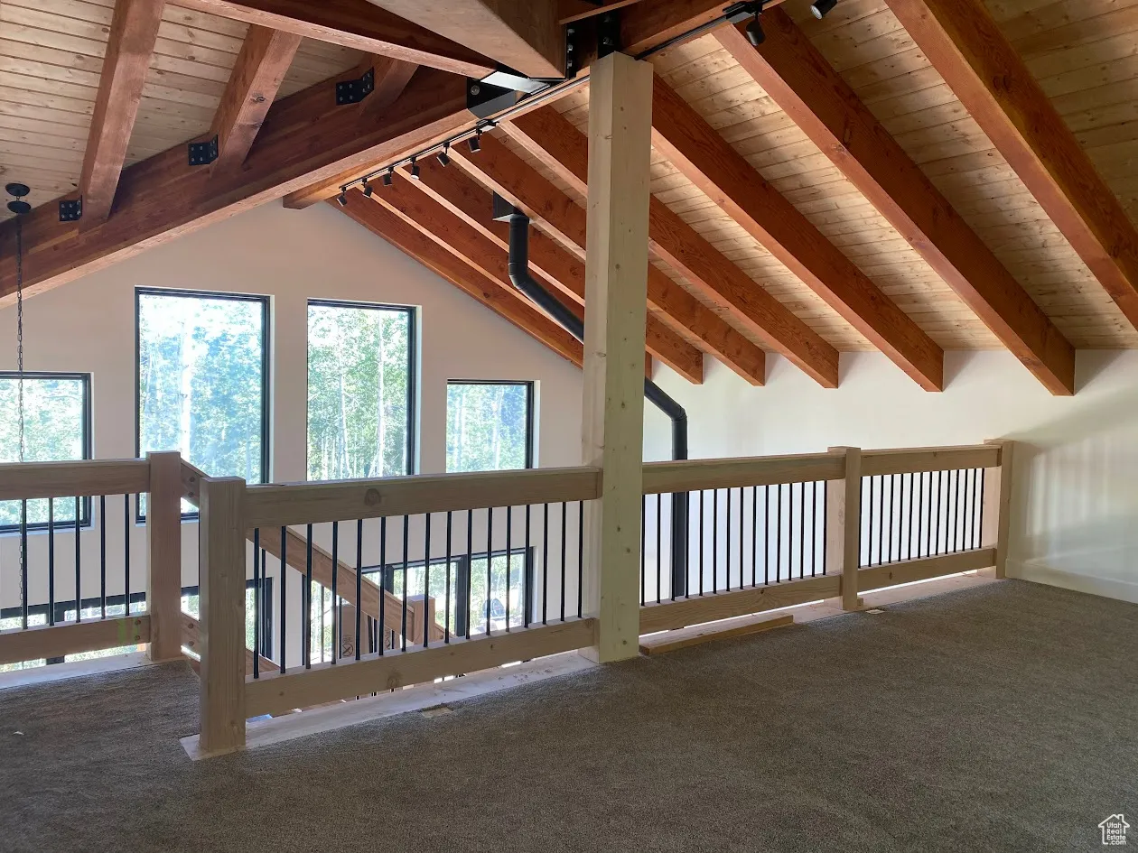 Unfurnished living room featuring wood ceiling, plenty of natural light, and carpet floors