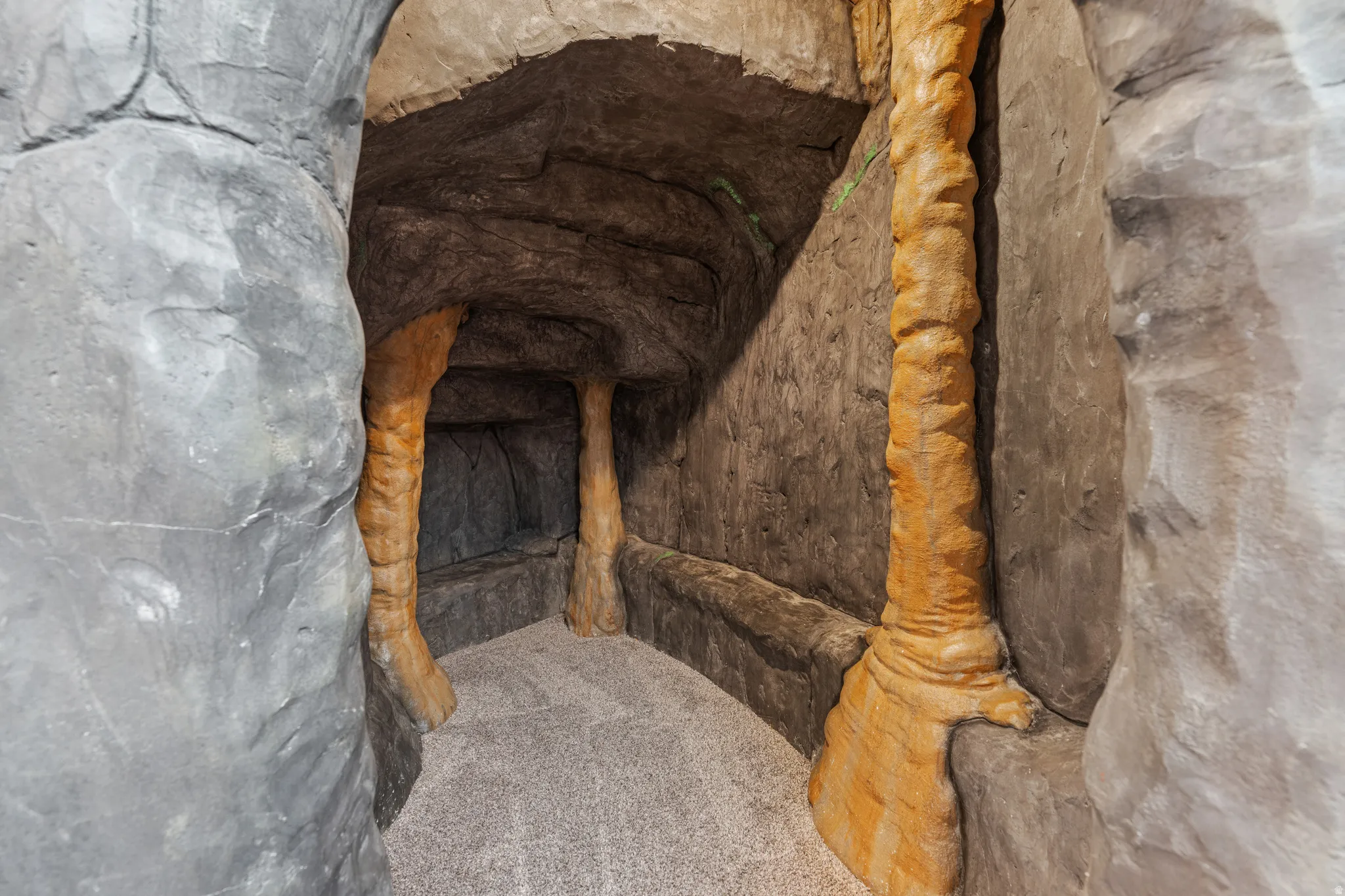 Thematic cave-like hallway with textured rock-finish walls and ceiling, featuring integrated column structures