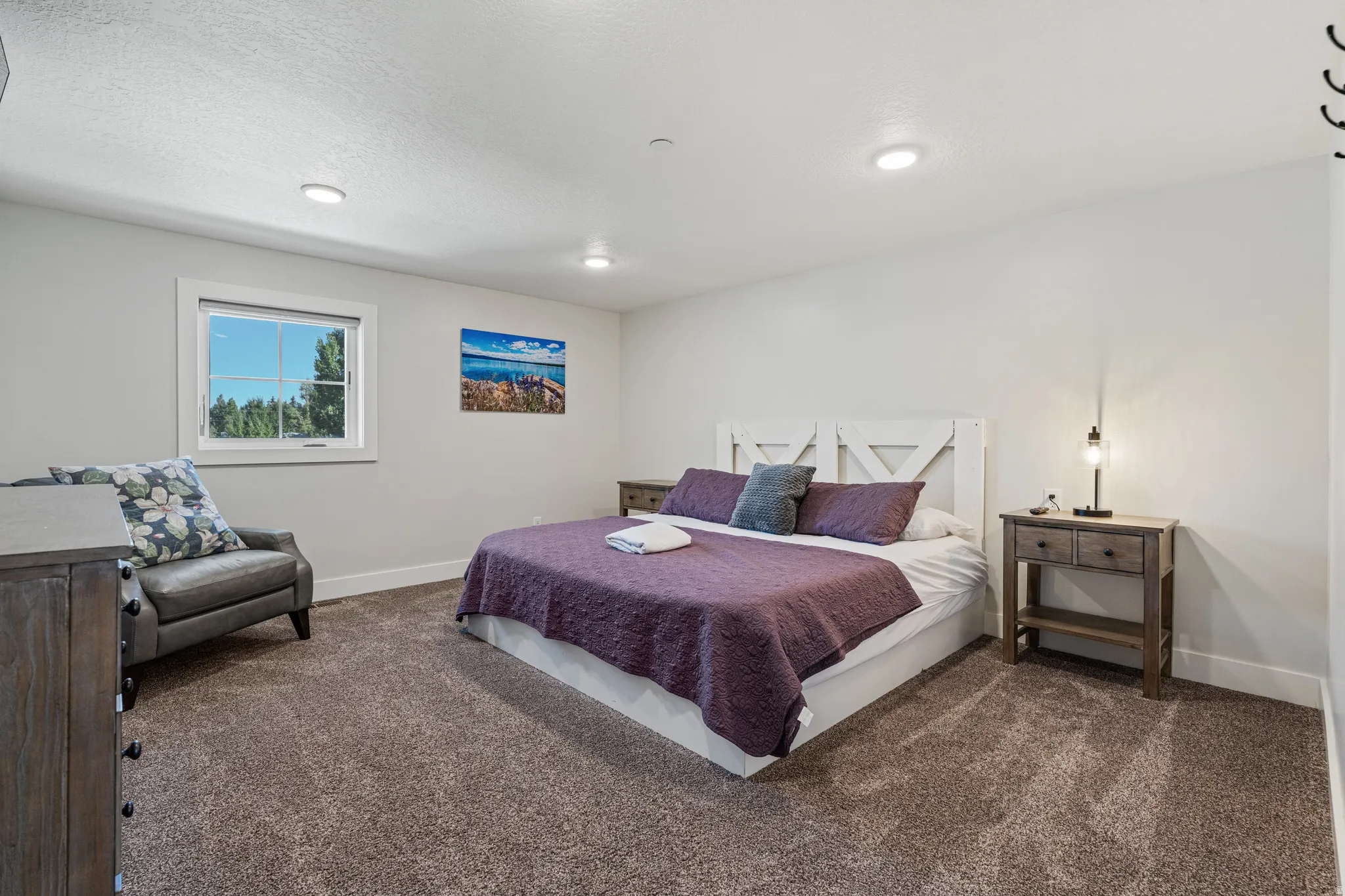 Recessed lighting, window with white trim, light-toned wall paint, and textured carpeting
