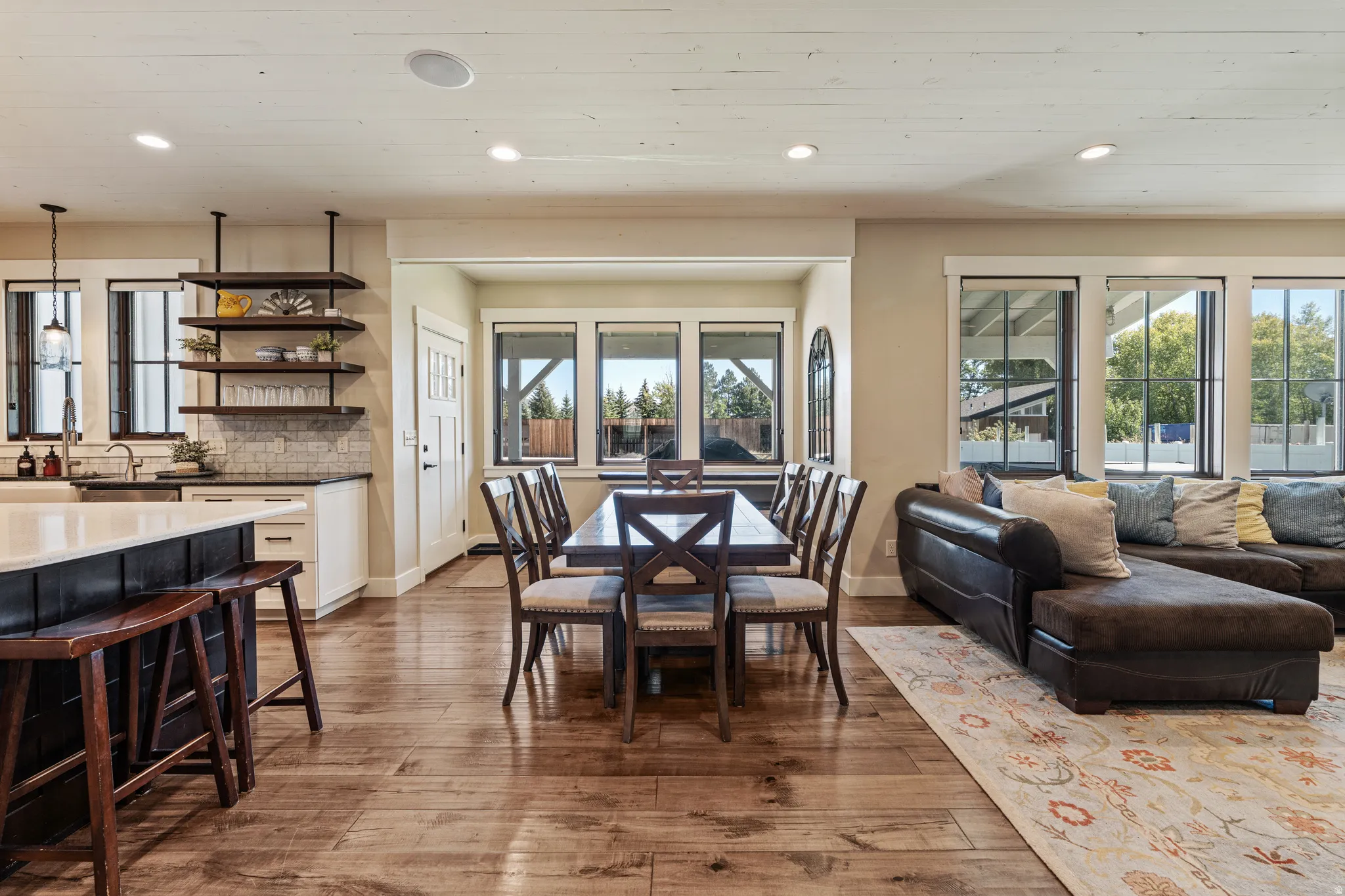 Open-concept living area with wood-finish flooring, recessed lighting, and large windows