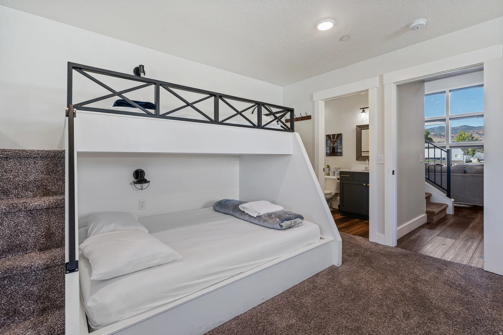 Built-in bunk beds with integrated lighting, a full bathroom with a dark vanity, and wood-finish flooring