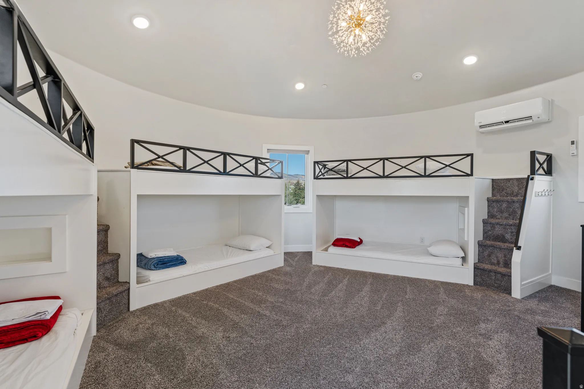 Curved wall room with built-in bunk beds, recessed lighting, and a modern chandelier