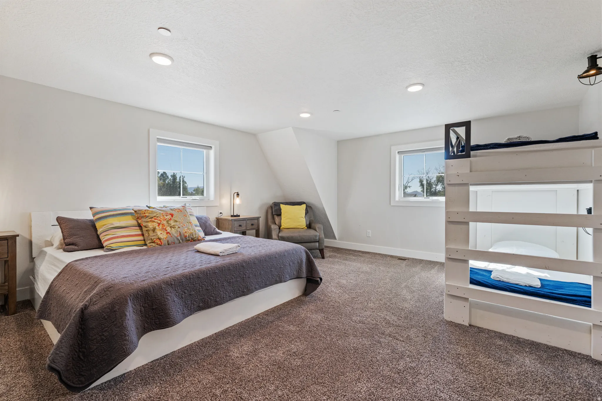 Spacious room featuring plush carpet, recessed lighting, white trim windows, and an accent wall