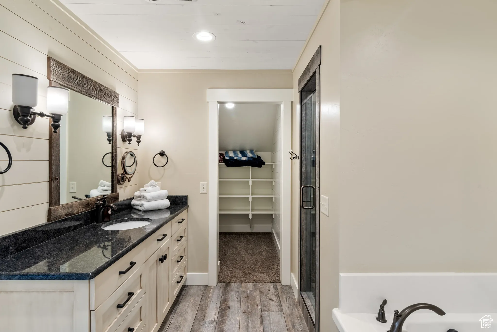 Full bathroom with wood finished floors, vanity, a walk in closet, and a shower with door
