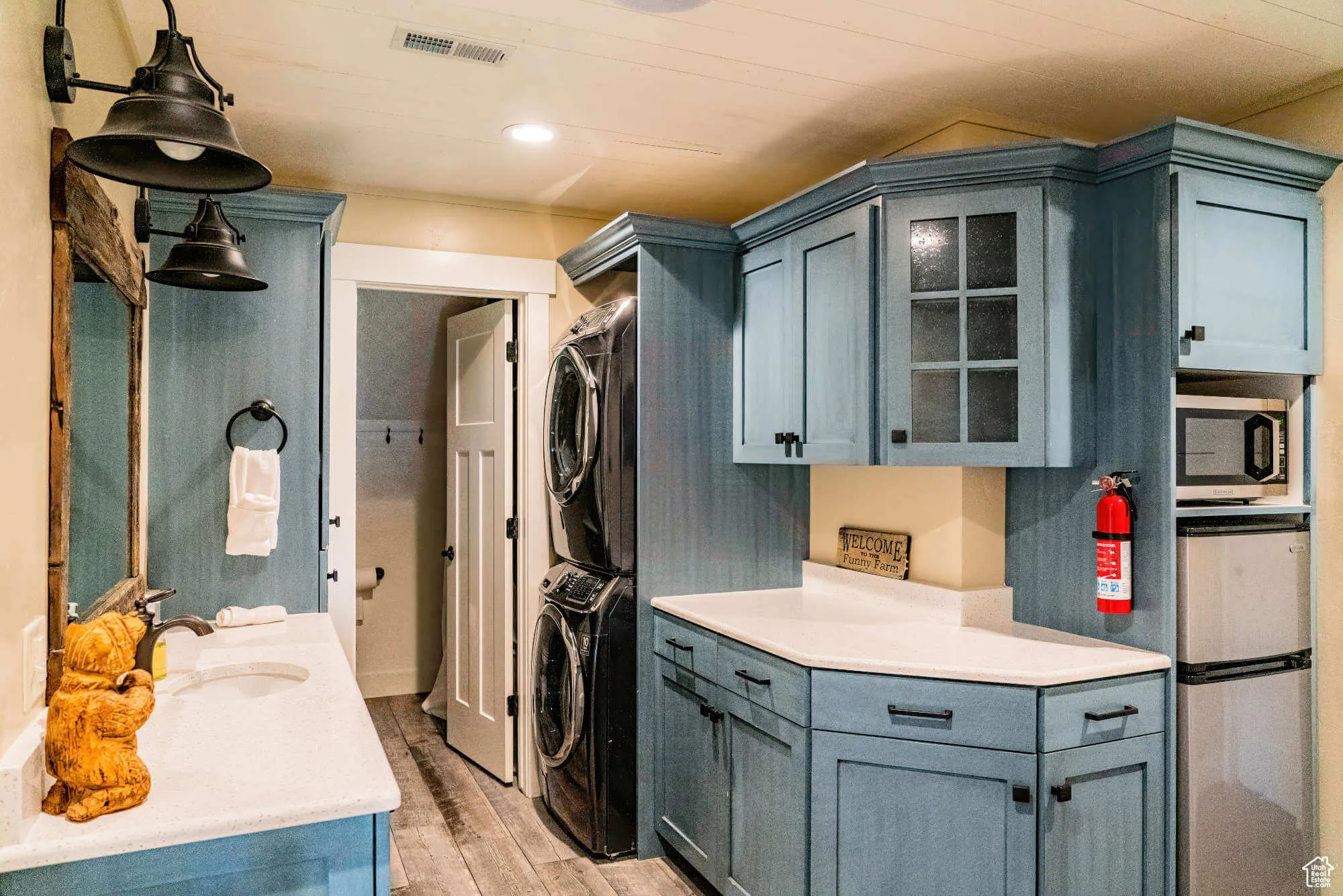 Laundry room featuring stacked washer and clothes dryer, light wood-style flooring, and crown molding