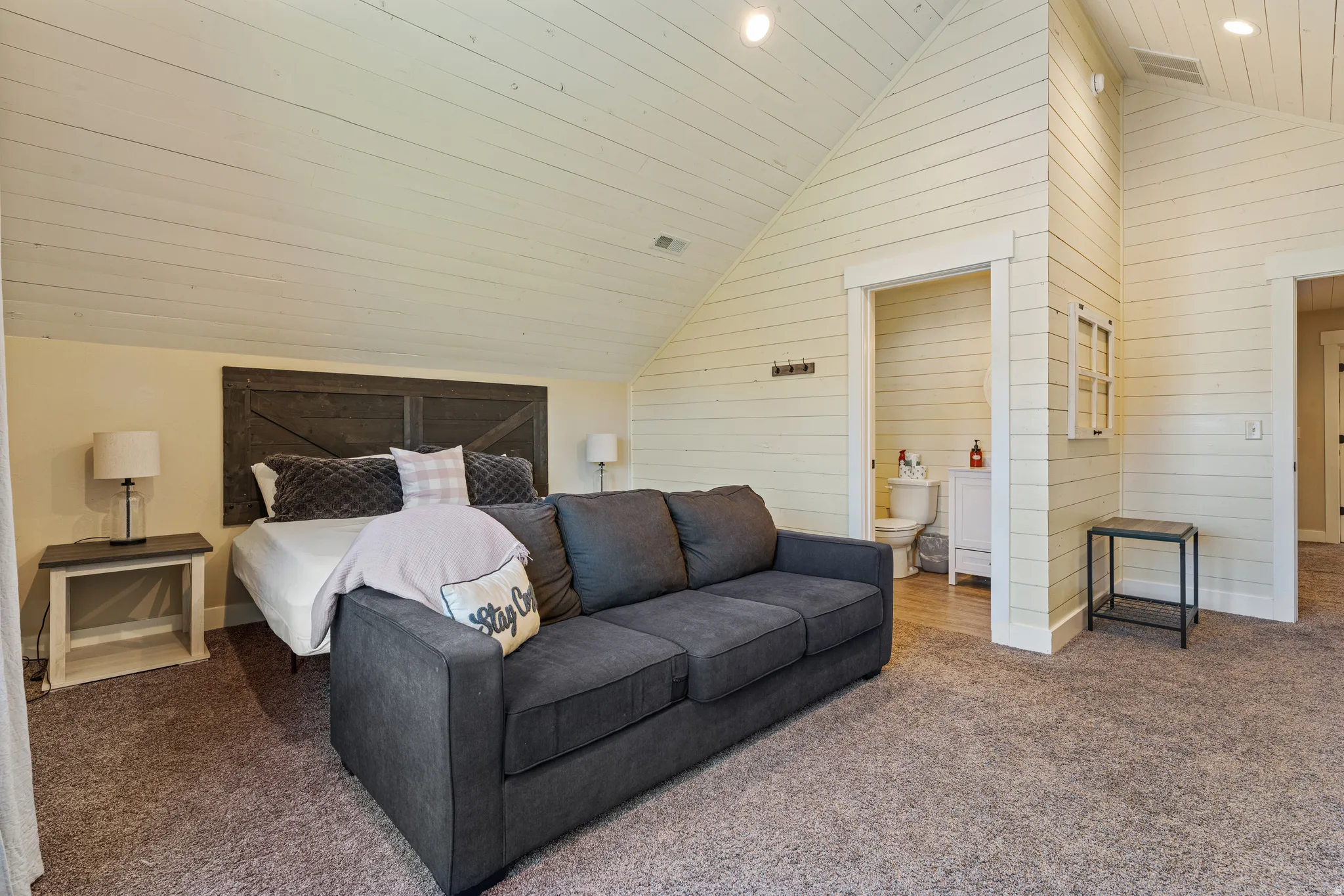 Vaulted ceiling with shiplap finish, shiplap wall accents, wood-finish headboard, and recessed lighting