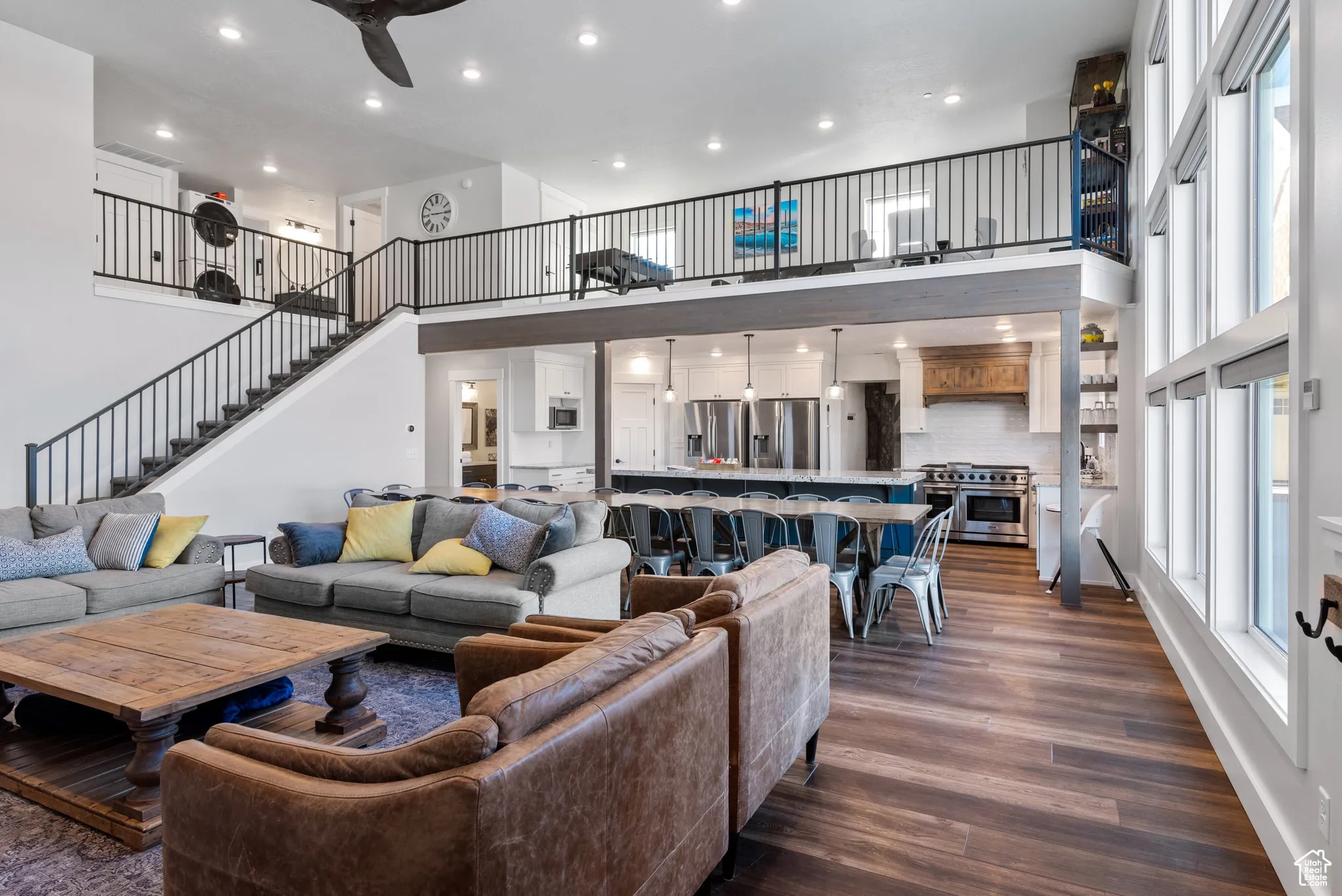 Living area with a towering ceiling, dark wood-style flooring, stairs, recessed lighting, and a ceiling fan