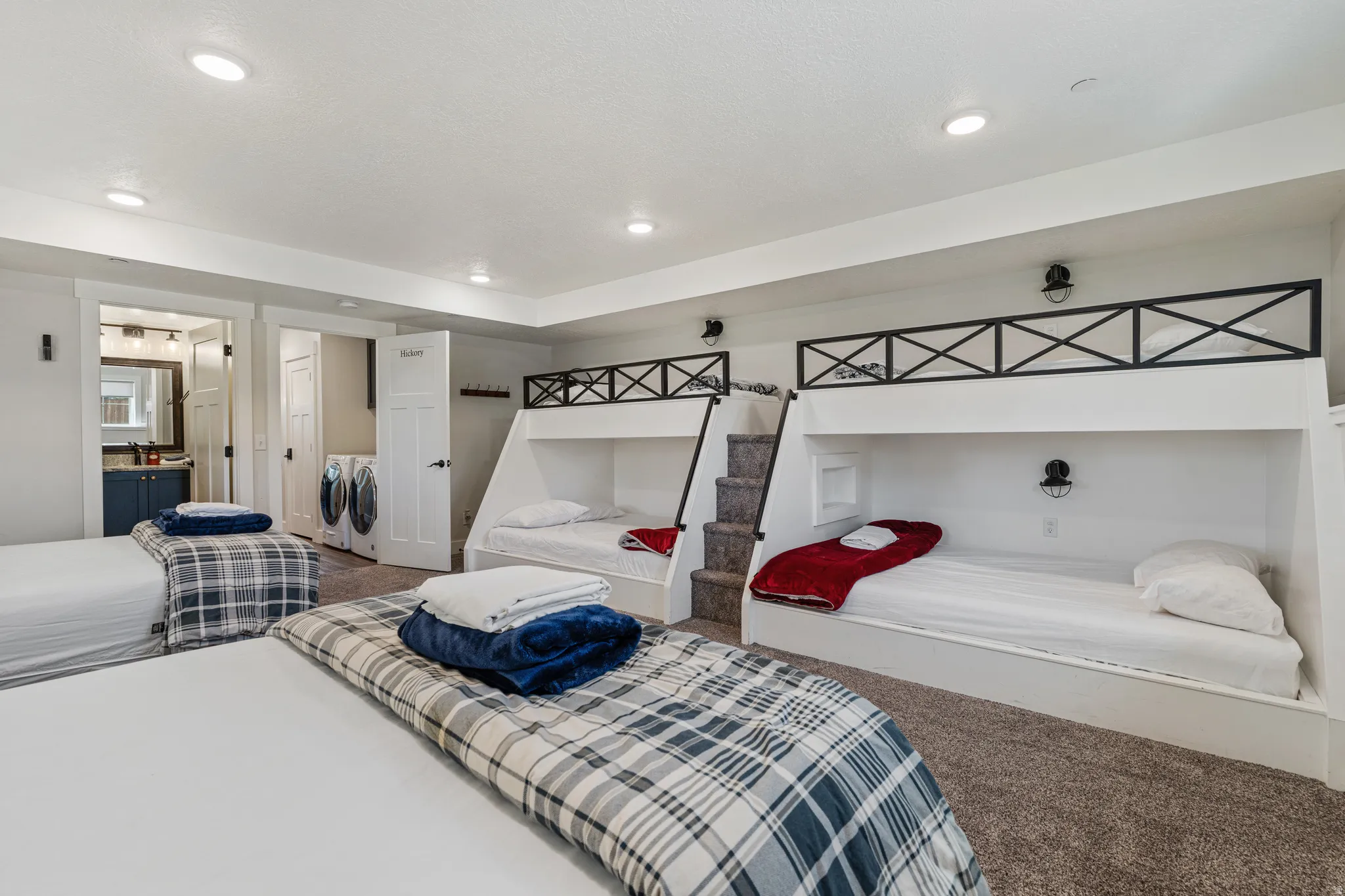 Built-in bunk beds with metal safety rails, recessed lighting, and wall-mounted sconces