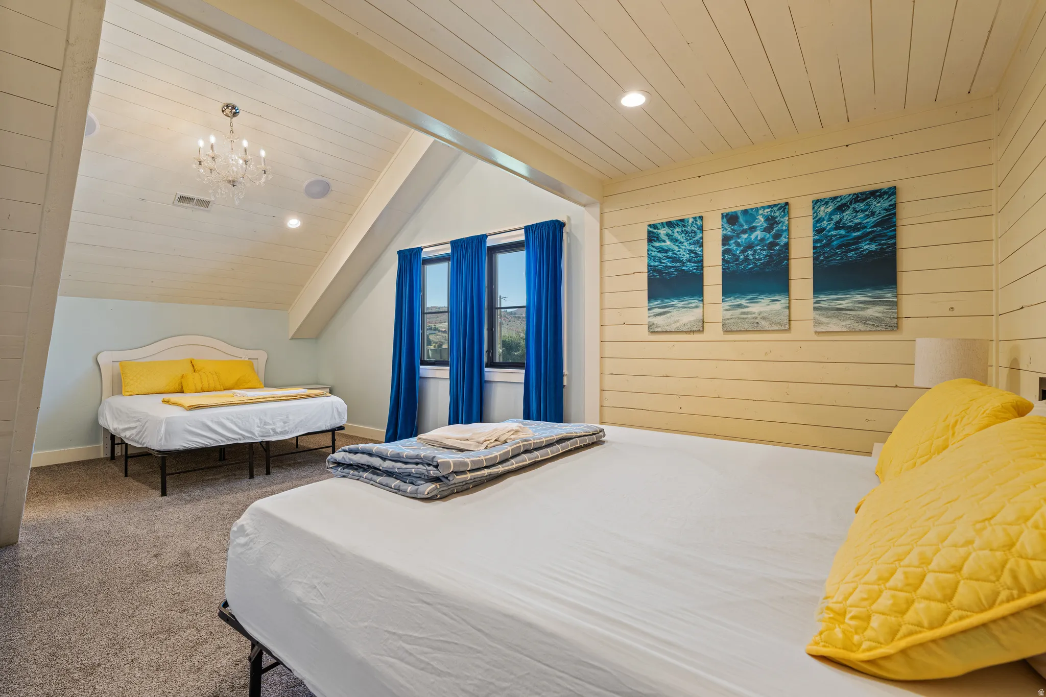 Slanted ceiling featuring a chandelier, recessed lighting, and wood-finish paneling