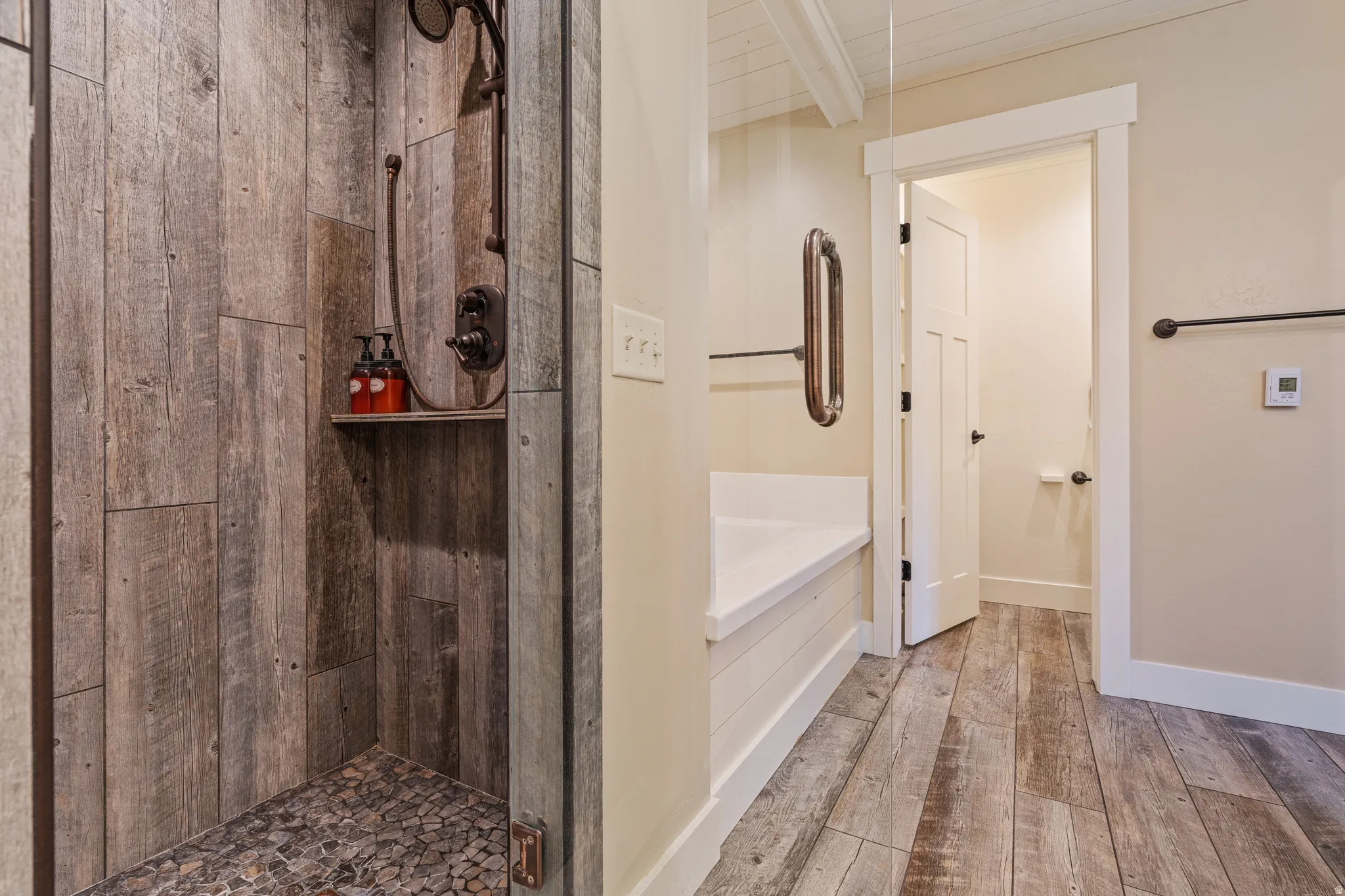 Walk-in shower with wood-finish paneling and pebble-finish floor