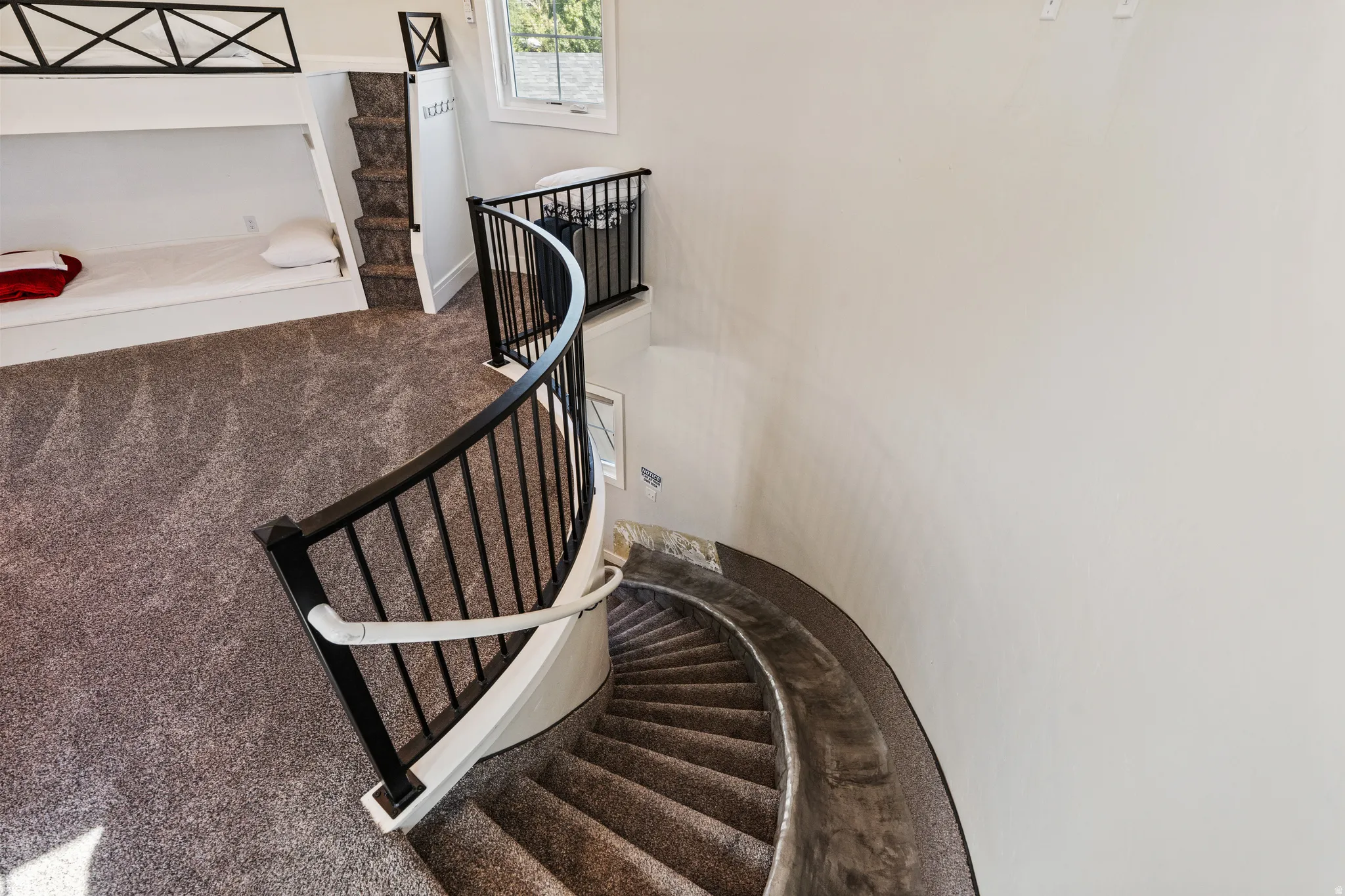 Curved staircase with black metal balusters and a white handrail