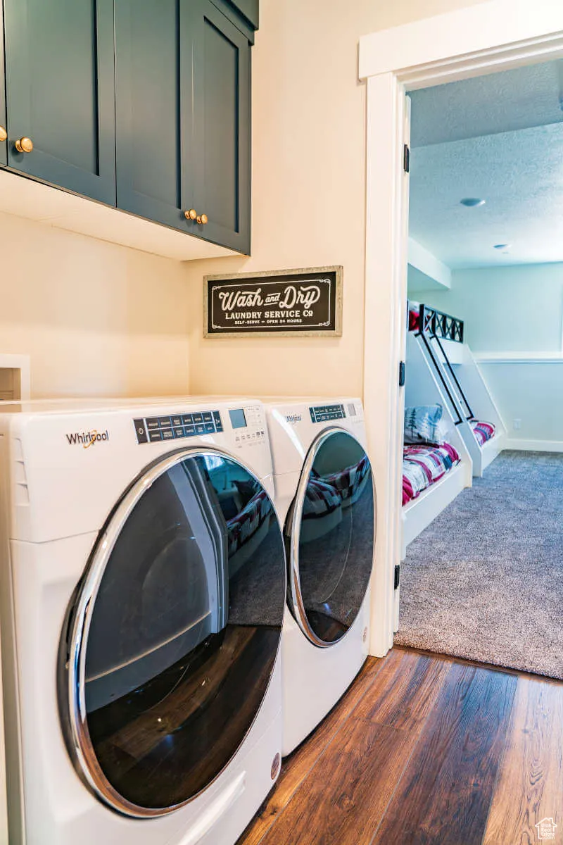 Laundry room featuring cabinet space, separate washer and dryer, and dark wood-type flooring
