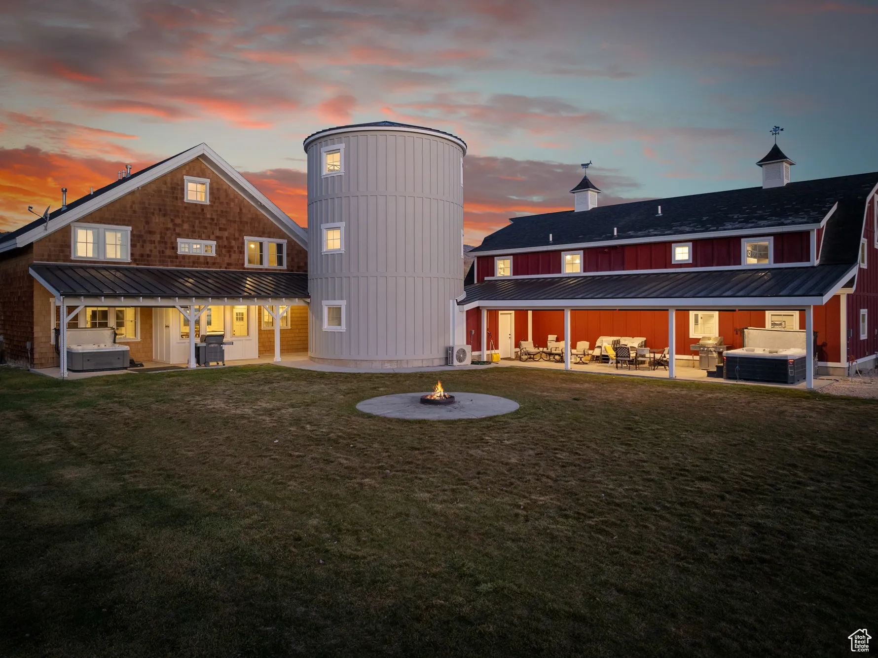 Back of property at dusk featuring a hot tub, a fire pit, a patio area, and a yard
