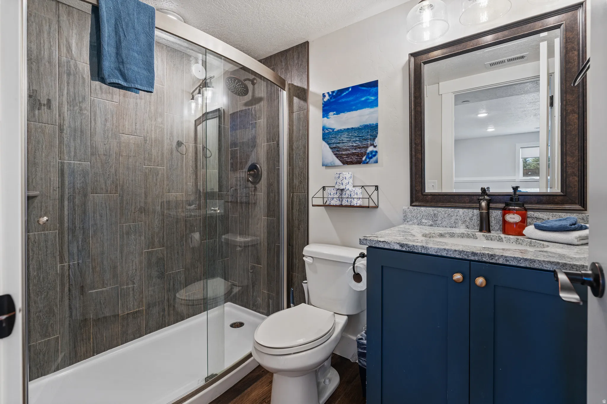 Walk-in shower with wood-look tile surround and glass enclosure