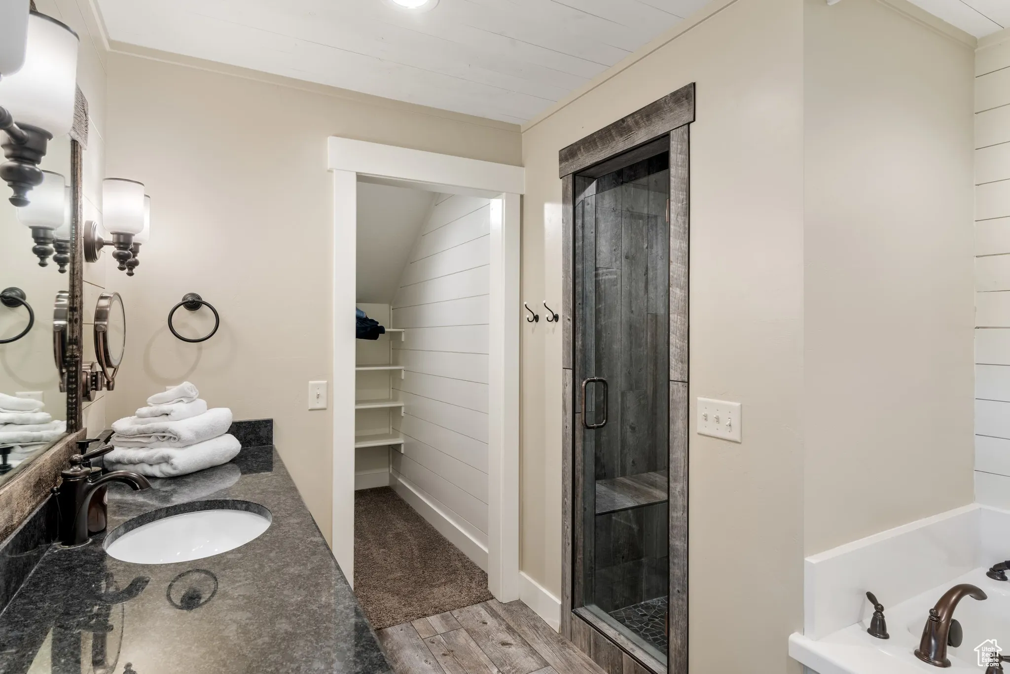 Full bathroom with a stall shower, a garden tub, vanity, wood finished floors, and a spacious closet