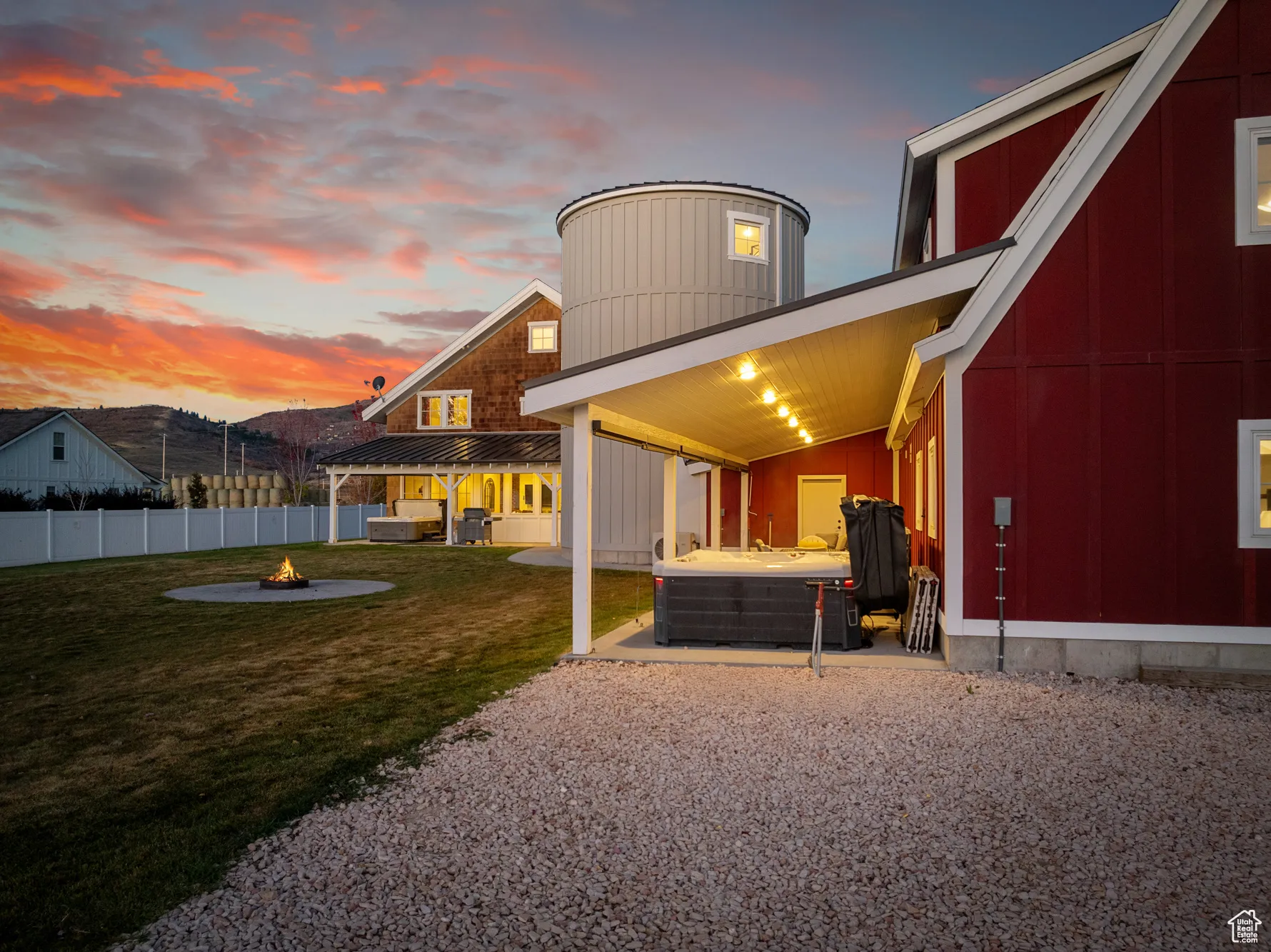 Back of property with a fire pit, a hot tub, and a patio area