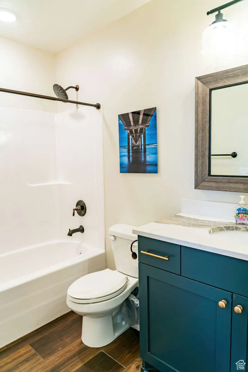 Full bathroom with wood finished floors, vanity, toilet, and shower / bath combination