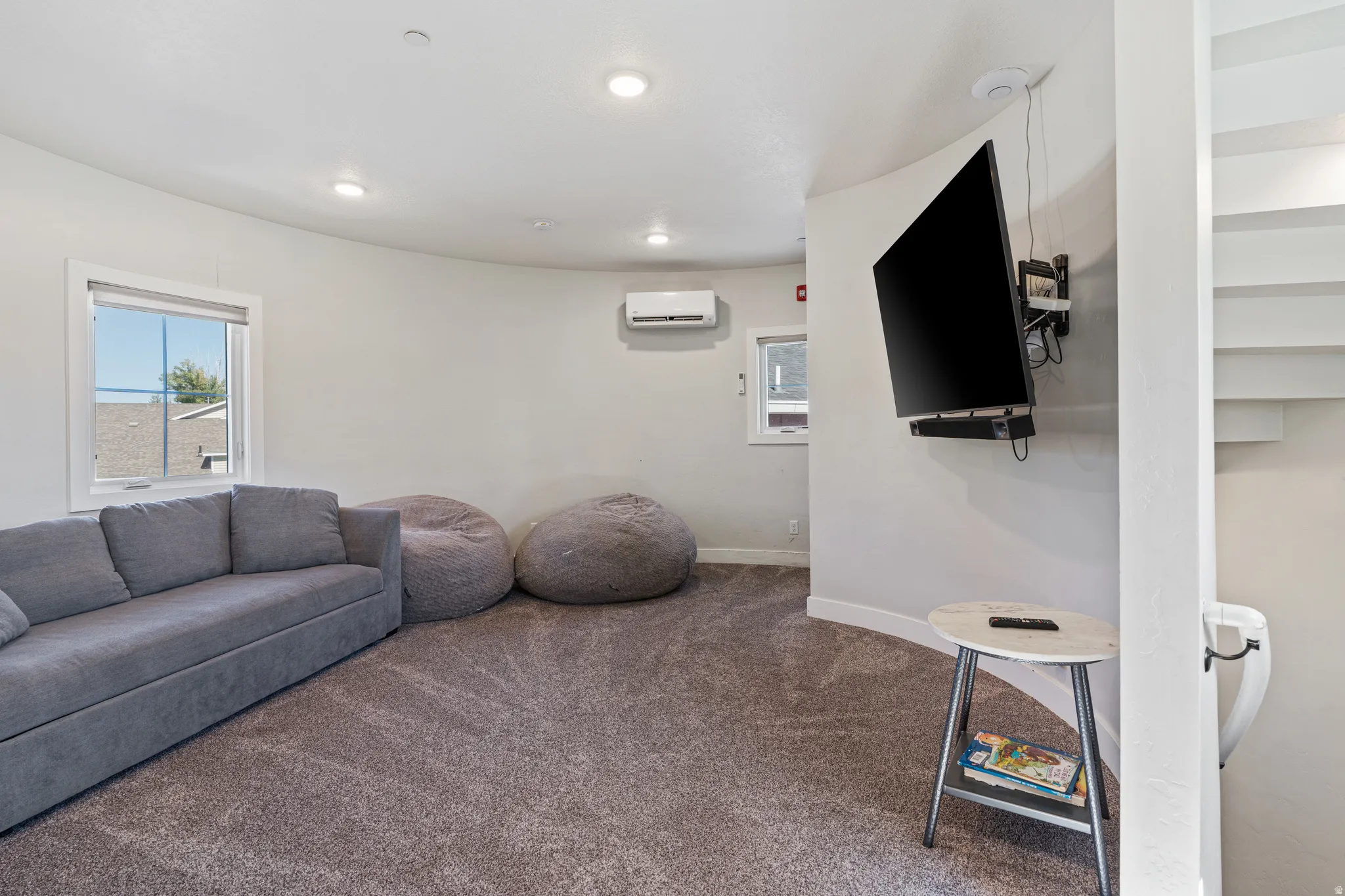 Recessed ceiling lighting, wall-mounted television, and a split-system air conditioning unit