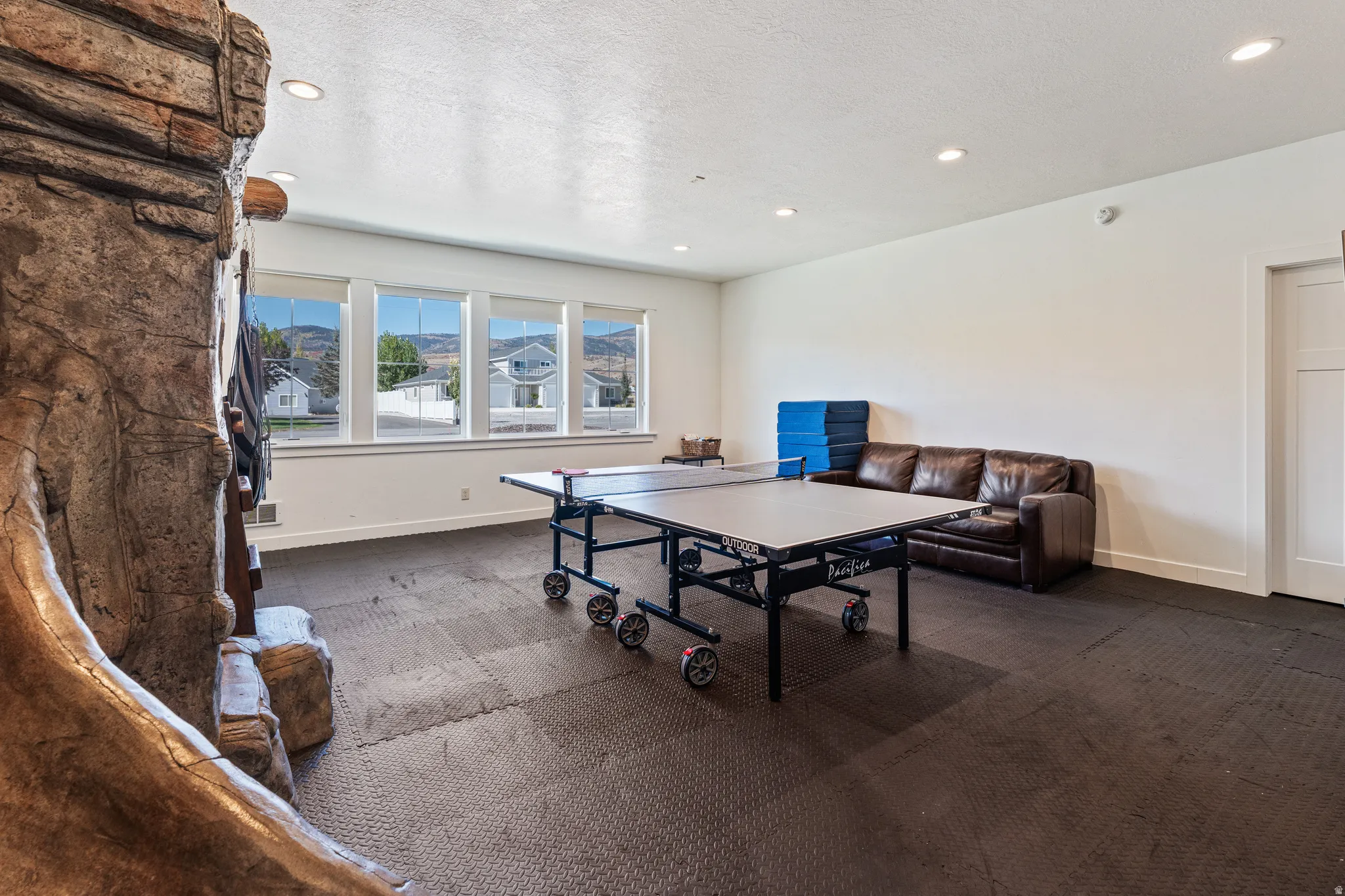 Spacious room with recessed lighting, large windows, and dark-toned floor tiles