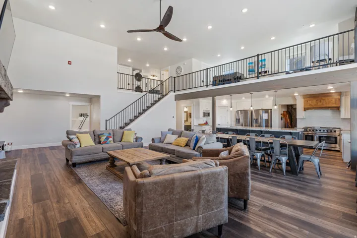 Open-concept living space featuring soaring ceilings with ceiling fan, recessed lighting, and a curved staircase with metal railings