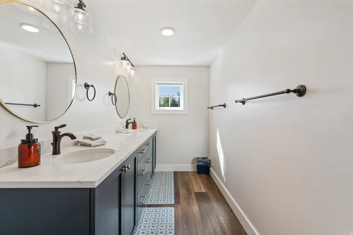 Dual vanities with undermount sinks, quartz countertops, dark wood-finish flooring, and recessed ceiling lights