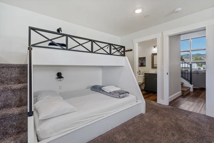 Built-in bunk beds with integrated lighting, a full bathroom with a dark vanity, and wood-finish flooring