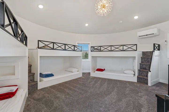Curved wall room with built-in bunk beds, recessed lighting, and a modern chandelier