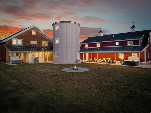 Expansive backyard featuring a central fire pit, covered patios, and an attached silo structure