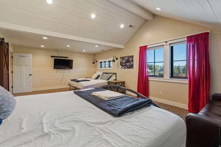 Vaulted ceiling with wood-finish paneling, recessed lighting, accent shiplap wall, and a barn door