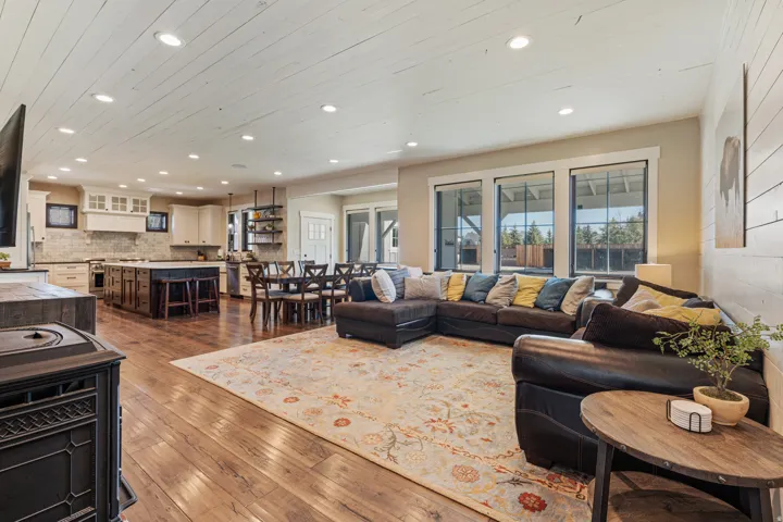 Open-concept living space with wood-finish flooring, recessed lighting, white shiplap ceiling, and a prominent kitchen island with seating