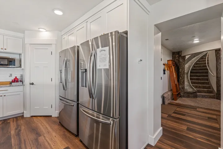 Stainless steel appliances, recessed lighting, white cabinetry, wood-finish flooring, and a curved staircase