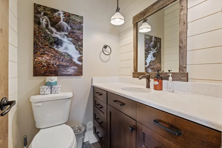 Vanity with a white countertop and integrated sink, dark wood-finish cabinetry, and a bronze-finish faucet