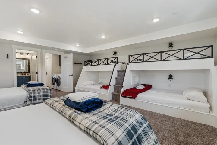 Built-in bunk beds with metal safety rails, recessed lighting, and wall-mounted sconces