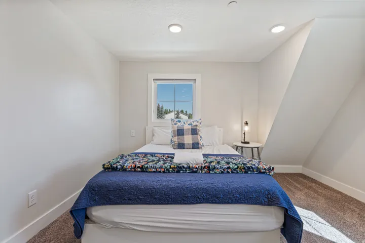 White painted walls, recessed ceiling lighting, a single window, and sloped ceiling details