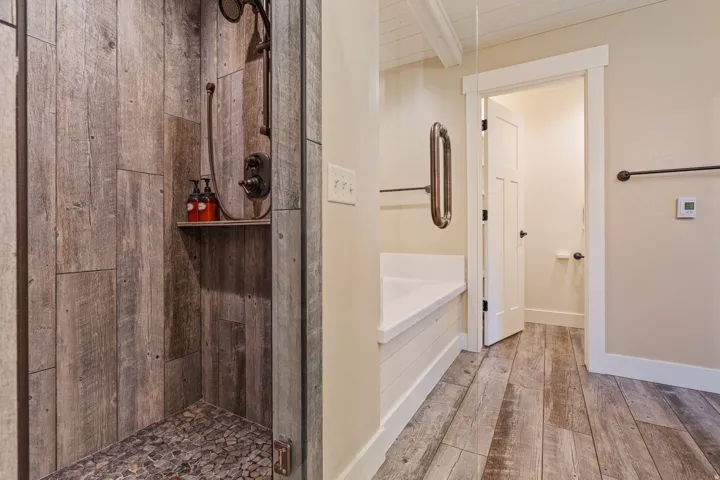 Walk-in shower with wood-finish paneling and pebble-finish floor