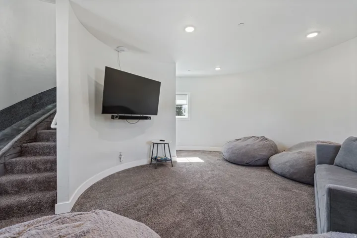 Carpeted staircase with white railing, curved wall, recessed lighting, and a single window