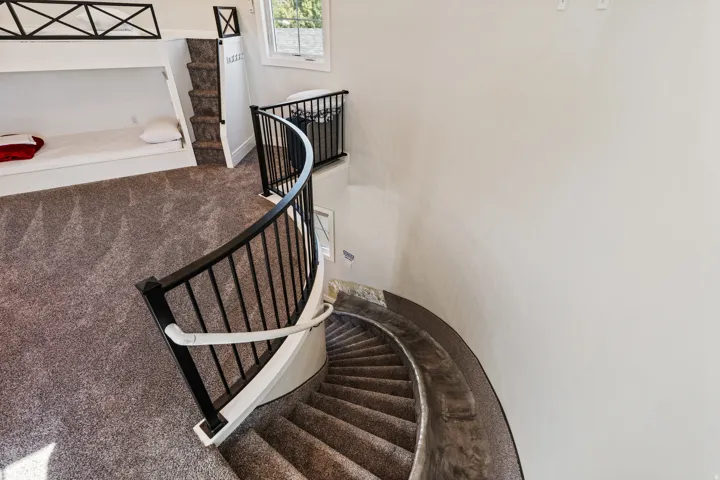 Curved staircase with black metal balusters and a white handrail
