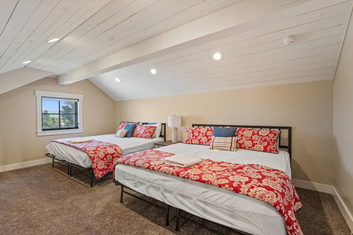 Angled ceiling with exposed beams, recessed lighting, and a window with a dark frame