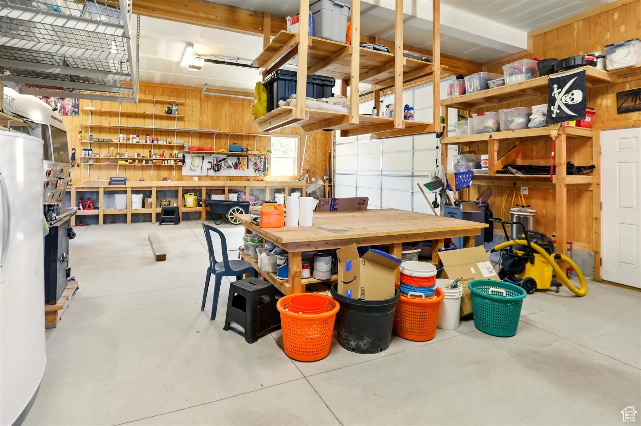 Garage featuring a workshop area, fridge, and wood walls