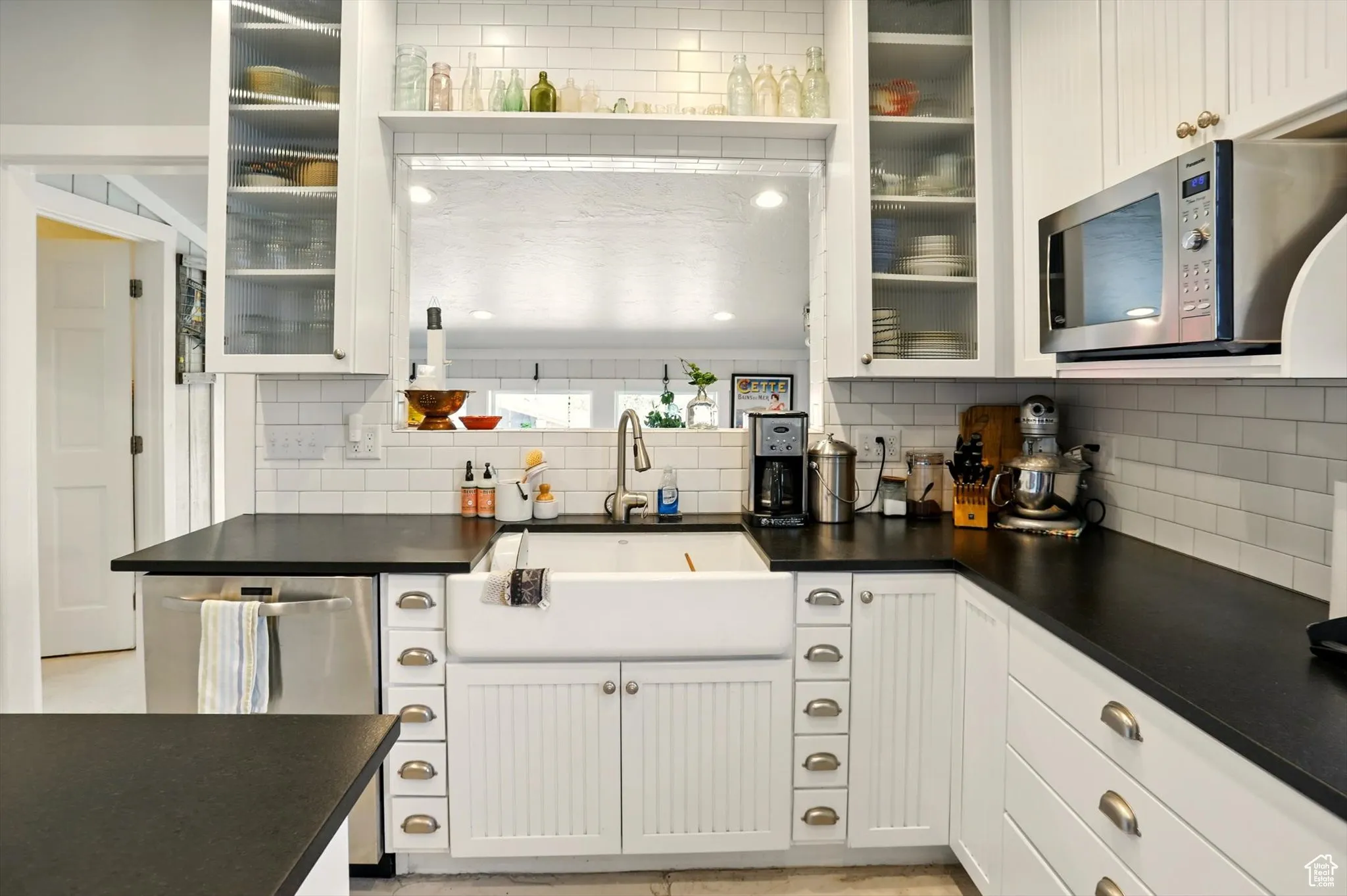 Kitchen with stainless steel appliances, a sink, tasteful backsplash, and dark countertops